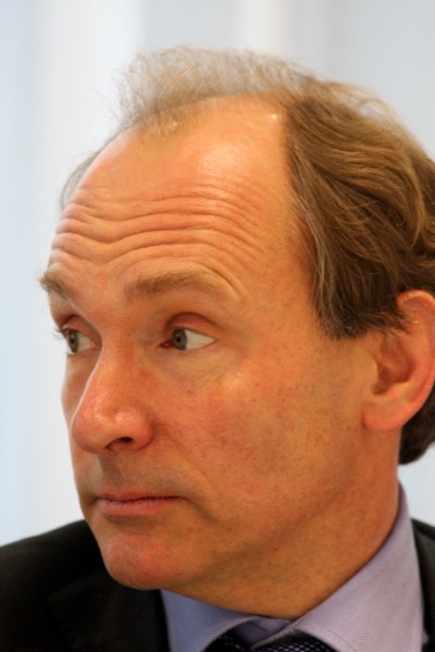 Portrait de Tim Berners-Lee, cheveux châtains et costume sombre, photographié de trois quarts, le regard tourné sur le côté.